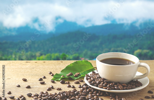 White Coffee cup on coffee beans around with mountain background