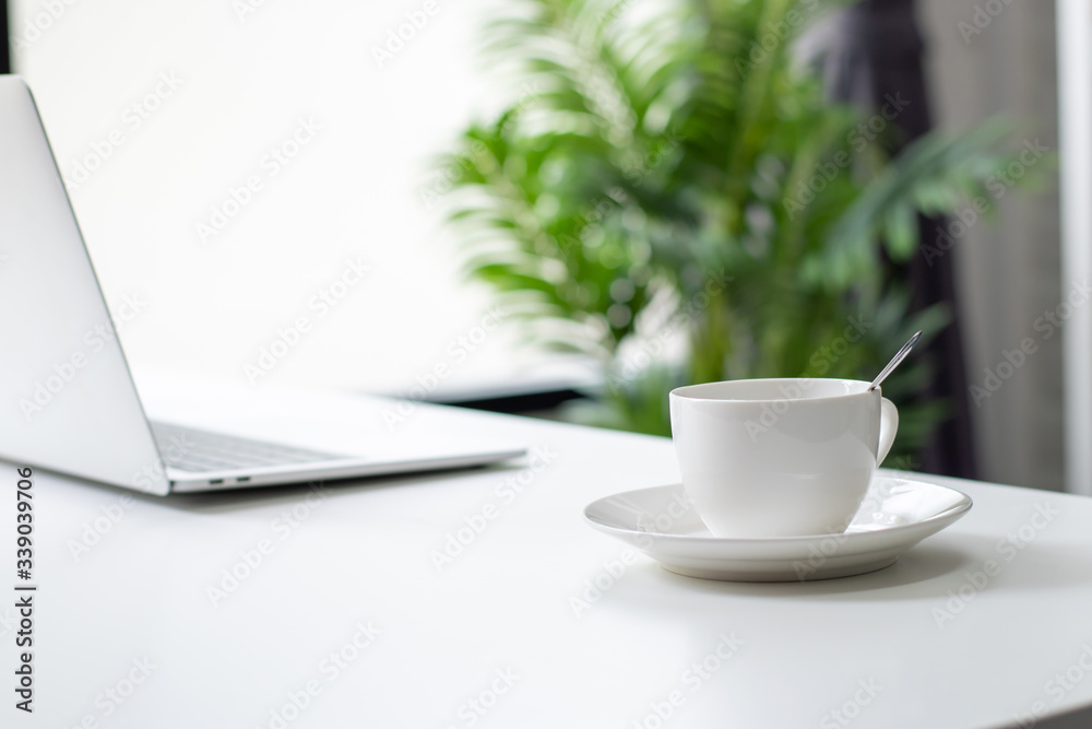Close up of a hot coffee cup for a young business man on a white desk with morning sunshine at home.