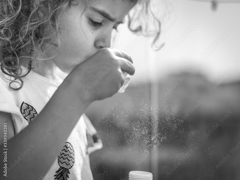 Isolated close up of a young girl during quarantine from the Corona Virus having fun on the balcony blowing soap bubbles- Israel Isolated close up of a young girl during quarantine from the Corona Virus having fun on the balcony blowing soap bubbles- Israel