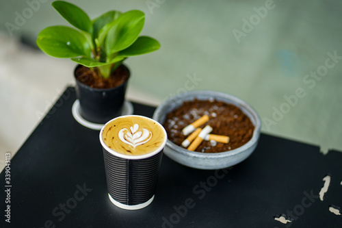 close up hot cappuccino and blur cigarette butts on black table