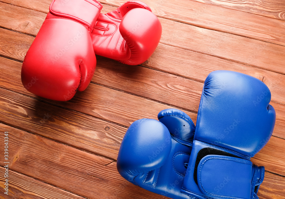 Two pairs of boxing gloves on a wooden background. Two pairs of boxing gloves in opposite corners.