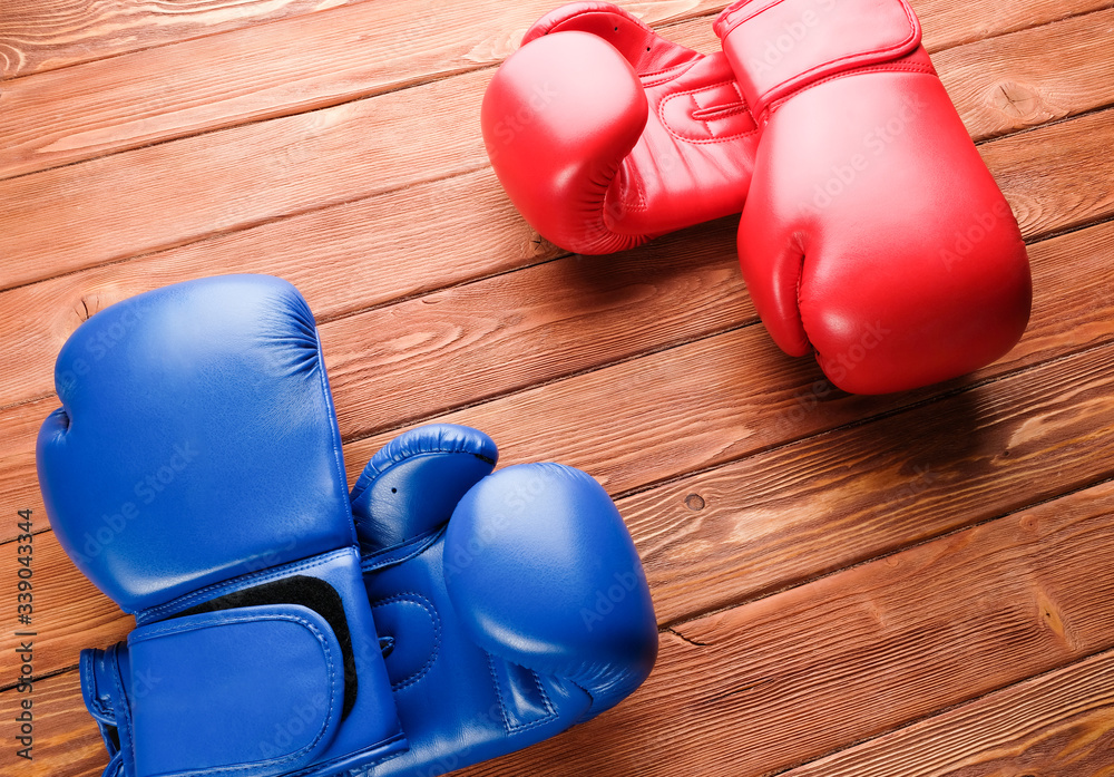 Two pairs of boxing gloves on a wooden background. Two pairs of boxing gloves in opposite corners.