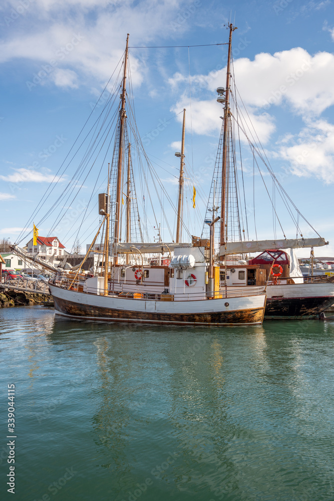 Whale watching ship or fishing vessel in Husavik harbour in Iceland during sunny day.