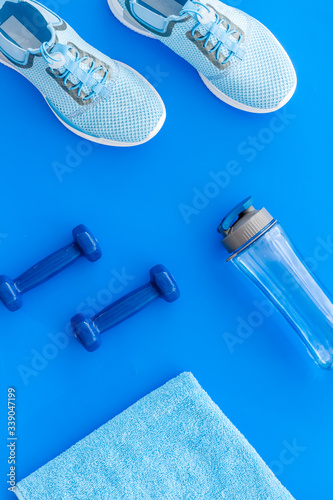 Sport flat-lay with dumbbells, towel, sneakers on blue background top-down