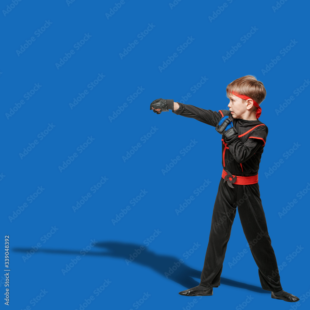 Naklejka premium Young boy in kimono practicing taekwondo and making hit