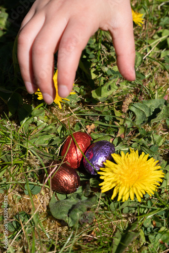 main d'enfant saisissant des œufs en chocolat dans un jardin