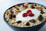 Healthy breakfast, bowl of oatmeal and yogurt with raspberry, nuts and dried raisins