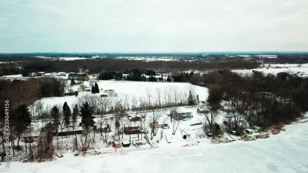 Aerial descending shot of cabins along the side of a frozen lake in the midwest. 4K Aerial descending shot of cabins along the side of a frozen lake in the midwest. 4K