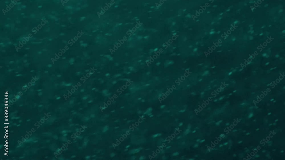 Macro shot of chaotic movement of tiny particles in aqua color liquid moving fast and gradually slowing down. Macro shot of chaotic movement of tiny particles in aqua color liquid moving fast and gradually slowing down.