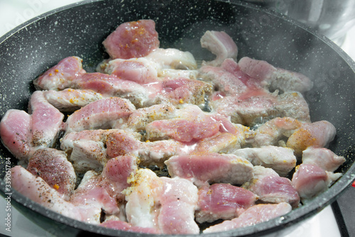 Pork fried in a black pan close-up