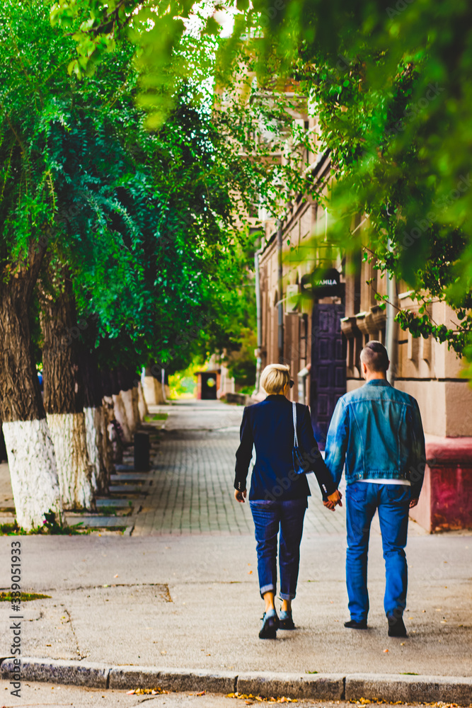 Man and woman walk down the street in the city holding hands