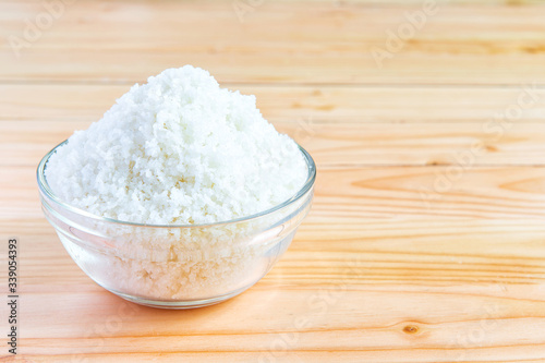 Sea salt in bowl on wooden background, Sea salt is salt that is produced by the evaporation of seawater. Used as a seasoning in foods, cooking, cosmetics and for preserving food..