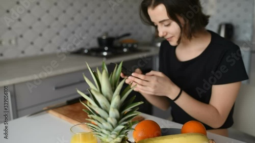 Young woman with vegetables smiling while esing mobile phone in kitchen. photo