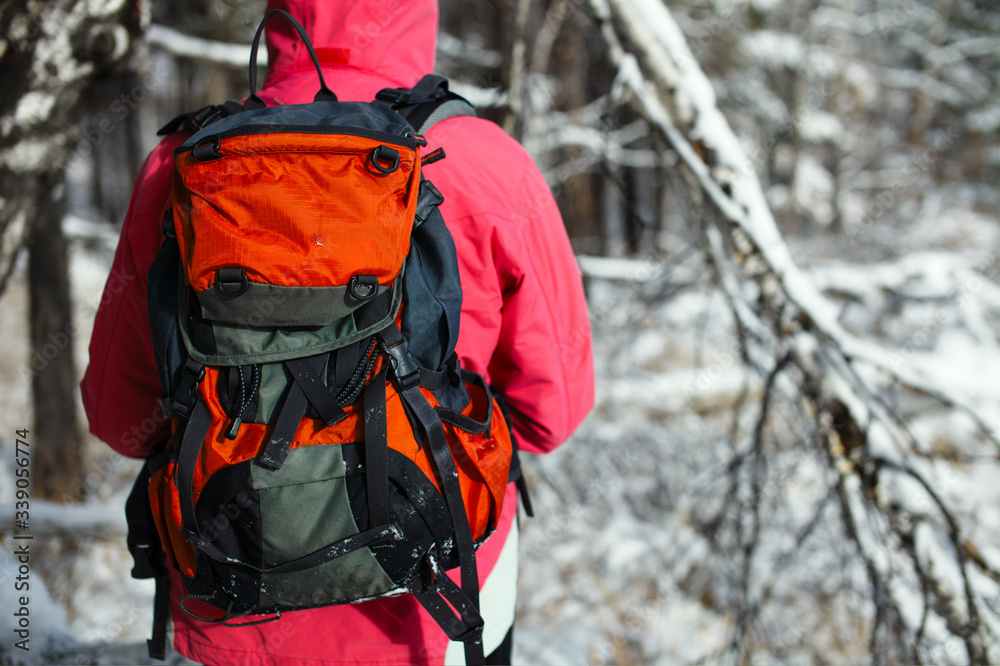 Tourist backpack behind the back of the traveller against the backdrop of a snow-covered landscape, back view, close-up. Tourist backpack behind the back of the traveller against the backdrop of a snow-covered landscape, back view, close-up.