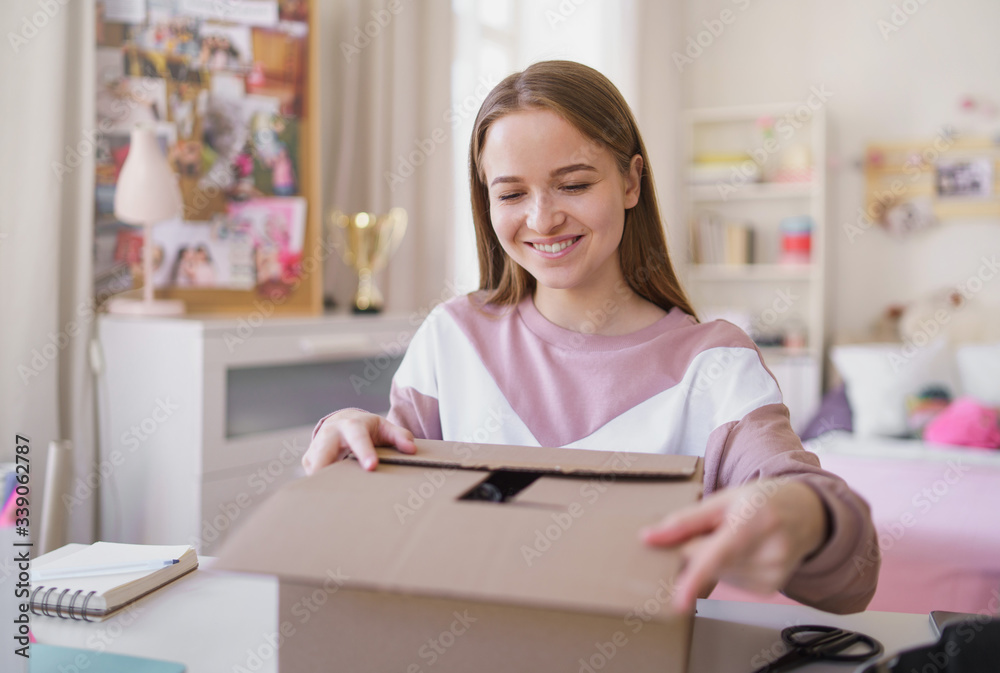 Young female student at the table, opening parcel box. Young female student at the table, opening parcel box.