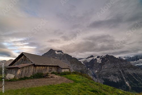 An alpine farm hut surrounded by Swiss countryside with the Eiger mountain peaks in the background in Grindelwald Switzerland