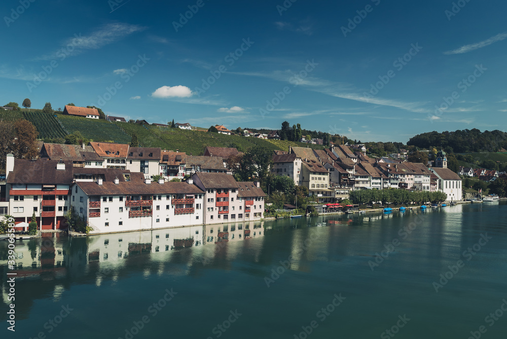 Reflections of medieval town houses and buildings along the river Rhine in the Swiss village of Eglisau in Switzerland