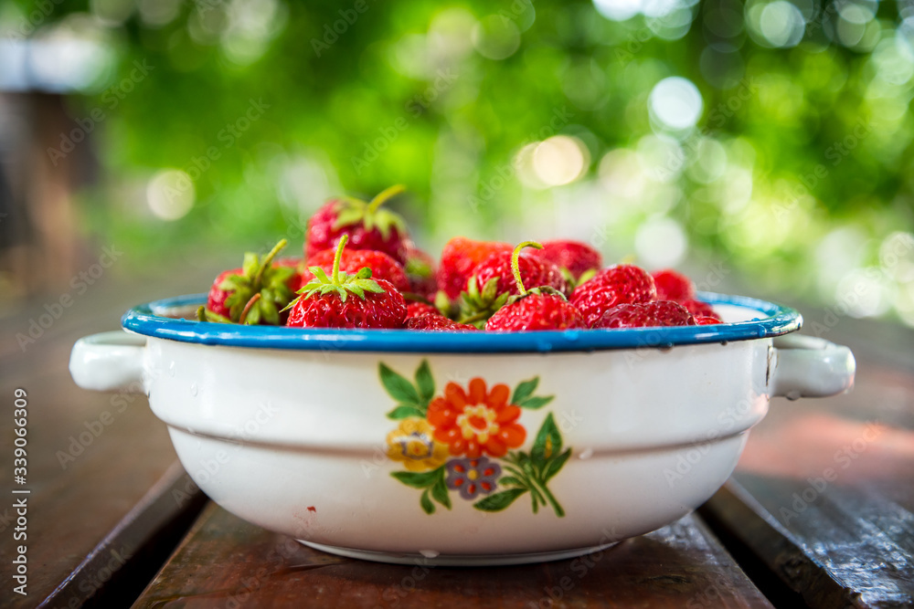 Plate with group of ripe, delicious strawberry on a brown wooden table. Selective focus. Shallow DOF. Blurred natural background Plate with group of ripe, delicious strawberry on a brown wooden table. Selective focus. Shallow DOF. Blurred natural background