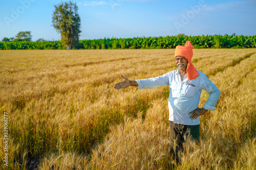 young indian farmer at golden wheat field