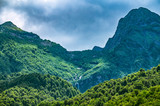 High green mountains with a high waterfall in cloudy spring or summer day.