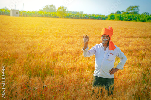 young indian farmer spreading his arms at wheat field