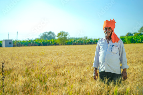 Young Indian farmer standing at wheat field