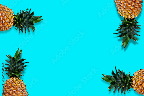 Flat lay pineapples with copy space on bright blue background. Seasonal fruit with blank space for your message.