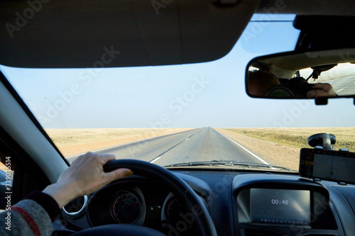 View from car window on the road and landscape with steppe, prairie, wilderness, plain and blue sky. Landscape through windscreen in Kalmykia in Russia