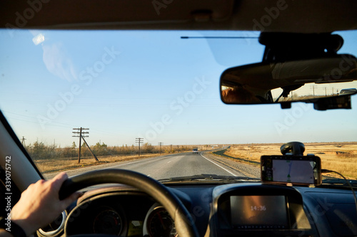 View from car window on the road and landscape with steppe, prairie, wilderness, plain and blue sky. Landscape through windscreen in Kalmykia in Russia