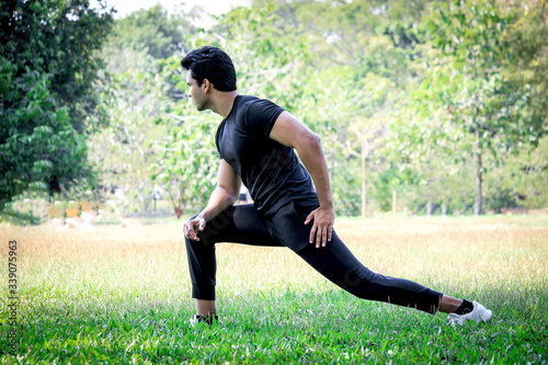 Young runner man stretching body before exercise run outdoor in park, hansom sport male jogger athlete training and doing workout in garden