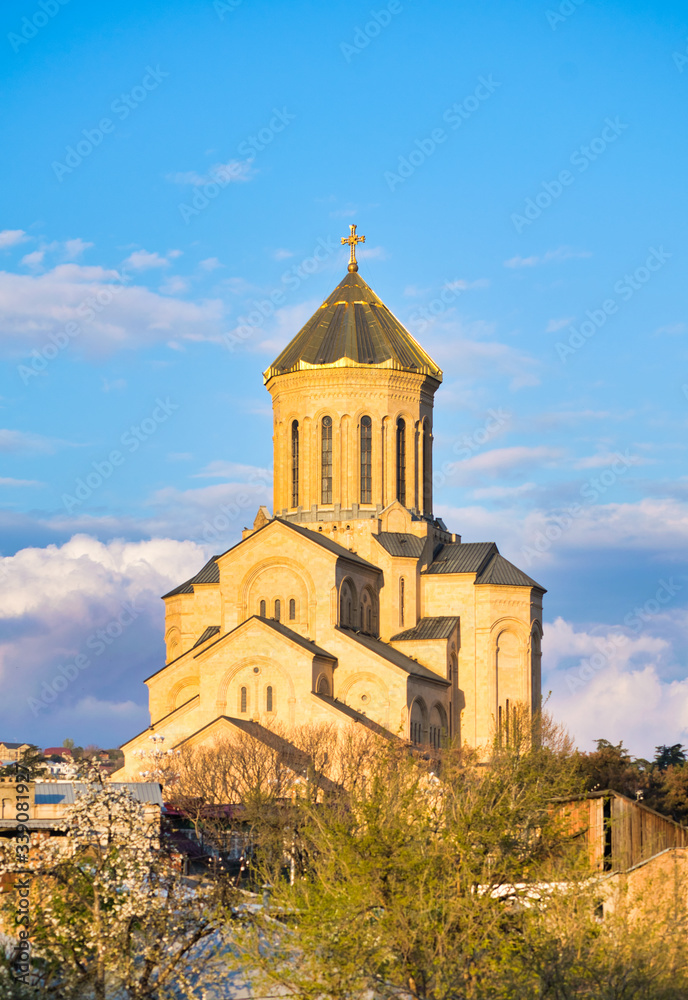 Orthdodox holy trinity church in Tbilisi with many hosues around and blooming spring trees. Religion and culture of Kartvelians. Sakartvelo. Orthdodox holy trinity church in Tbilisi with many hosues around and blooming spring trees. Religion and culture of Kartvelians. Sakartvelo.