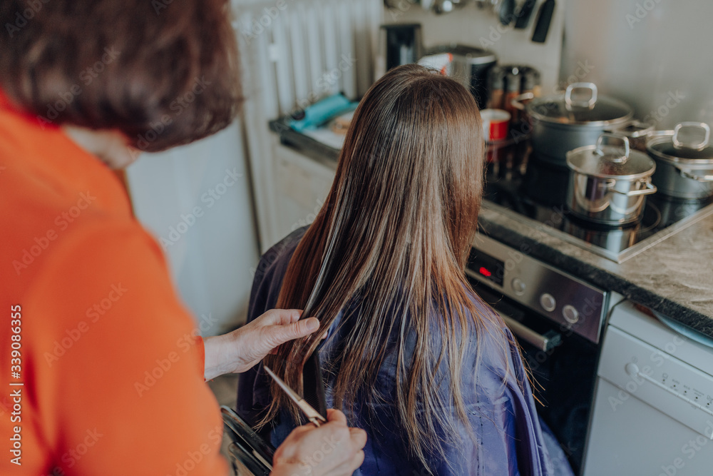 mature woman cuts hair to young beautiful woman with long hair at home, because of quarantine mature woman cuts hair to young beautiful woman with long hair at home, because of quarantine