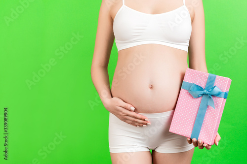 Wallpaper Mural Cropped image of pregnant woman in white underwear holding pink spotted gift box at green background. Waiting for a baby girl. Copy space Torontodigital.ca