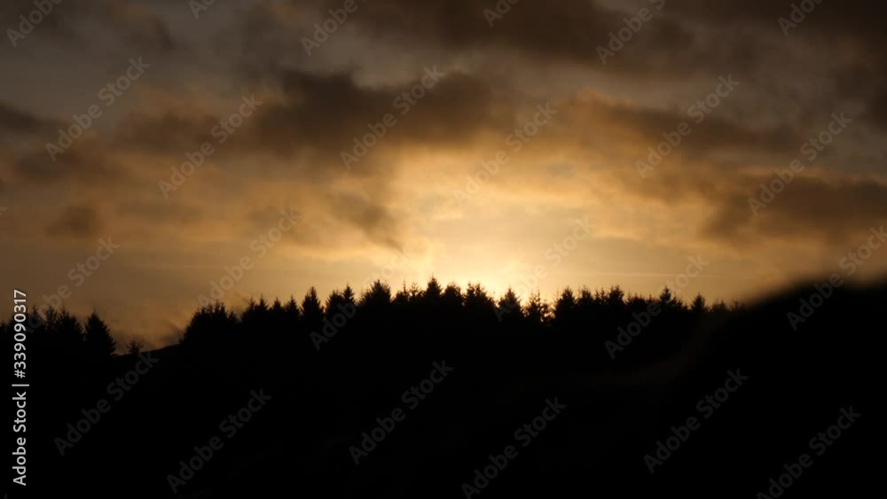 Slow mo sunset clouds passing over silhouetted forest Slow mo sunset clouds passing over silhouetted forest