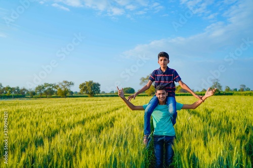 Brother piggyback his little brother in wheat field, rural india