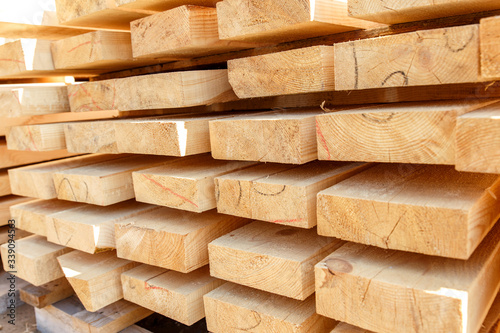 Stack of new wooden studs at the lumber yard. Timber on the construction site to dry. Background of sawed and processed wood of coniferous breeds.