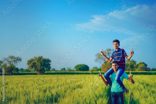 Brother piggyback his little brother in wheat field, rural india