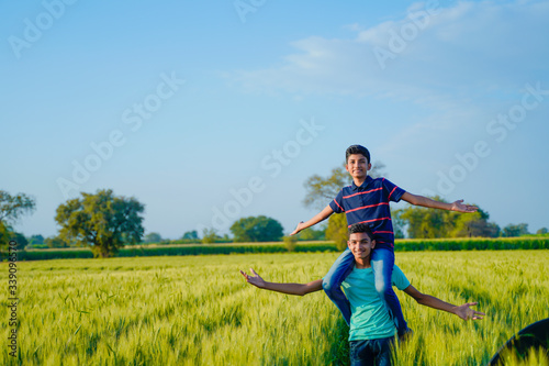 Brother piggyback his little brother in wheat field, rural india