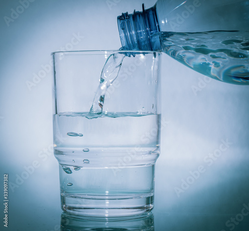 Wasser aus Plastikflasche in das Glas giessen