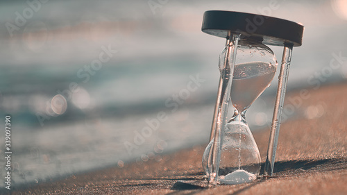 Hourglass at beach coast as time passing concept for business deadline, urgency and running out of time. © Evgeniy