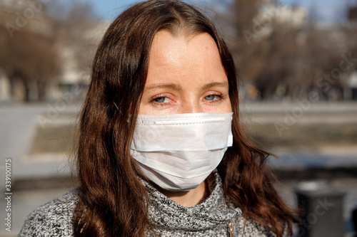 A woman in a medical mask walks alone on the street during the quarantine. Portrait of a female in a protective face mask against coronavirus.