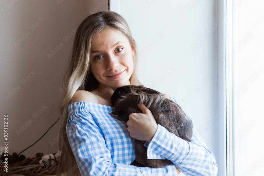 Pet and Easter concept - Happy girl hugging brown rabbit at home.