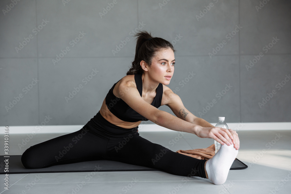 Photo of young athletic woman stretching her leg while working out Photo of young athletic woman stretching her leg while working out