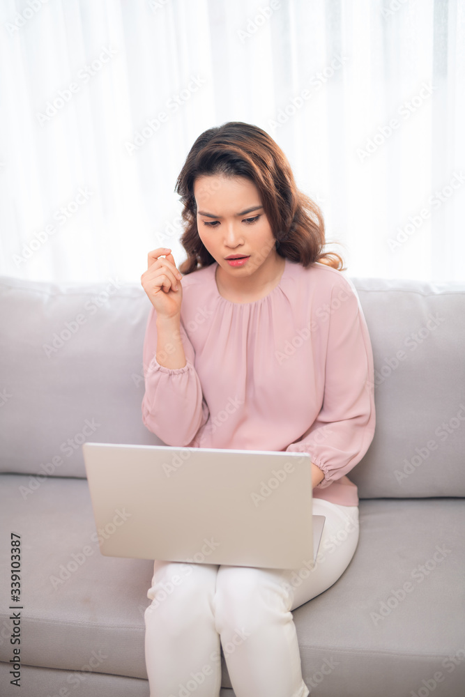 Confused Asian woman when using laptop on sofa at home. Confused Asian woman when using laptop on sofa at home.