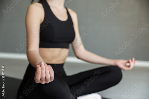 Cropped photo of athletic young woman meditating while sitting