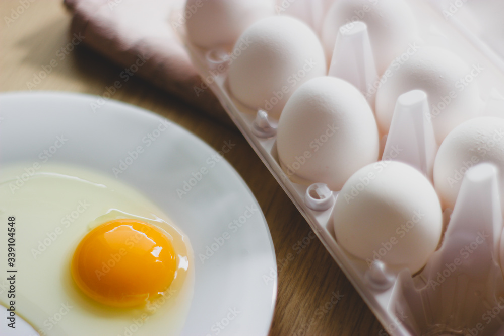 eggs in package and yolk on a white plate on the table eggs in package and yolk on a white plate on the table