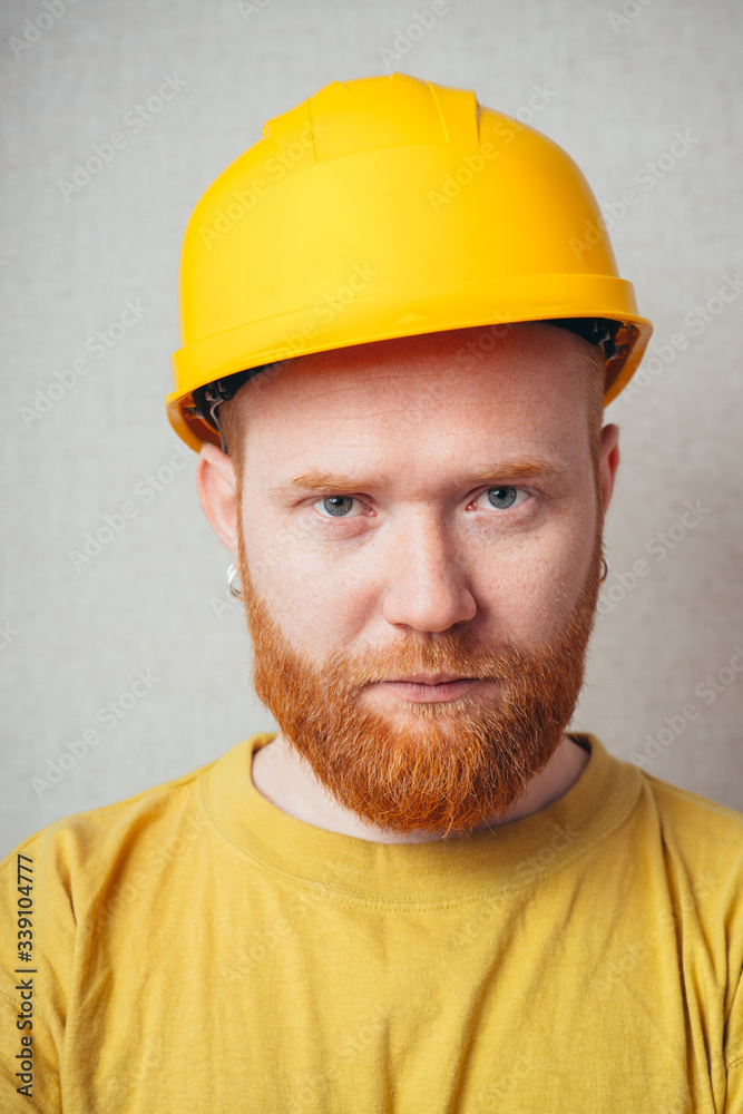 on a gray background man with a beard in a yellow shirt and yellow construction helmet on a gray background man with a beard in a yellow shirt and yellow construction helmet