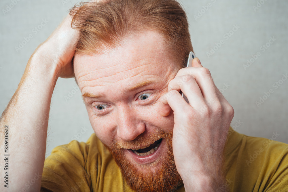 on a gray background man with a beard in a yellow T-shirt screaming on the phone on a gray background man with a beard in a yellow T-shirt screaming on the phone