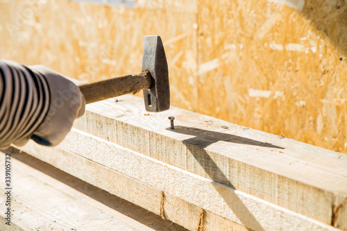 Carpenters uses a hammer to driving nail, Craftsmen and builder equipment. A man hammers an iron nail into a wooden beam.