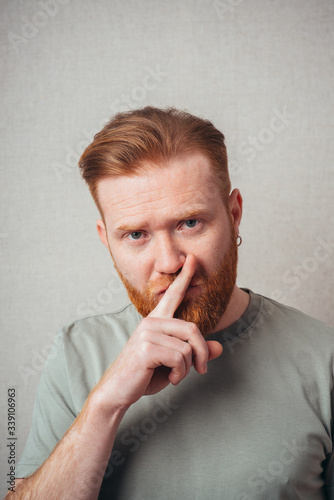 bearded man put his finger to his lips